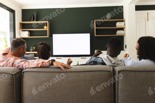 Preview: Excited diverse male and female friends watching sport on tv at home, copy space on screen