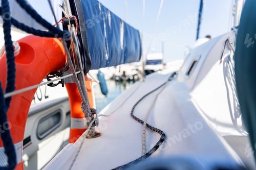Preview: Sailboat deck with lifebuoy and furled sail on a sunny day