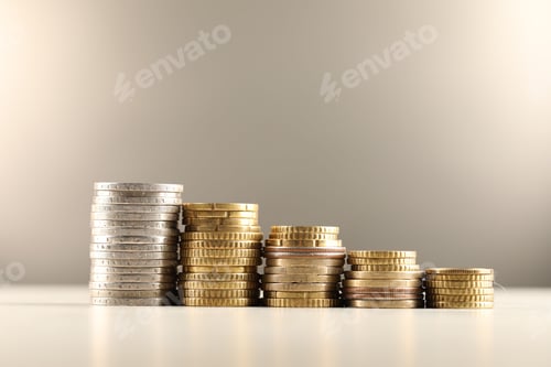 Vista previa: Pilas de diferentes monedas sobre una mesa luminosa sobre fondo gris, primer plano