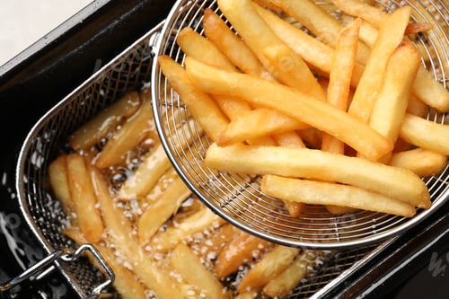 Preview: Delicious freshly prepared french fries in metal strainer, closeup