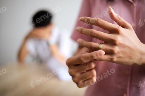 Preview: Emotional woman holding ring near distant husband, symbolizing possible separation.