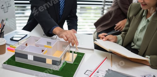 Preview: Real Estate Agents Discussing Marketing Plans with a Model House and Documents in a Modern Office