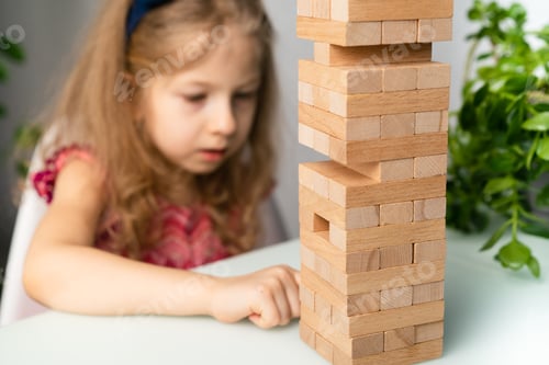 Preview: A little girl builds a tower of wooden cubes, a happy child plays a jeng board game, motor skills