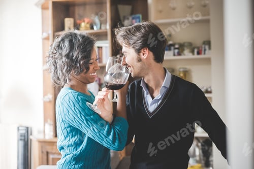 Preview: Young handsome mixed race couple in their house having a glass of red wine