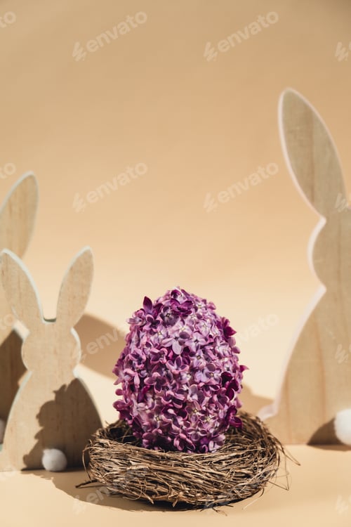 Preview: Wooden minimalism low-key bunny decor. Easter egg made of lilac spring flowers in pastel beige