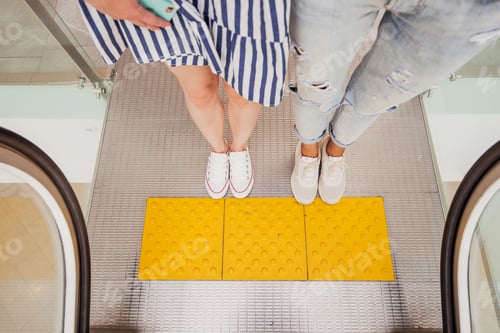 Preview: Two pretty young slim girls with dark hair,wearing casual style,stand at the escalator next to each