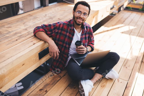 Preview: Happy male IT professional with netbook and takeaway cup