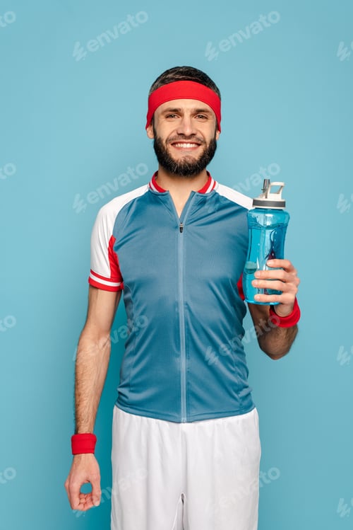 Preview: smiling stylish sportsman with water on blue background