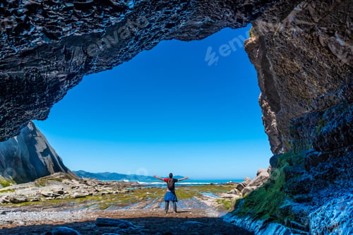 Preview: A hiker in the Algorri cove sea cave on the coast in the flysch of Zumaia, Gipuzkoa. Basque Country