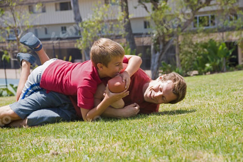 Preview: Boy tackling father playing american football in park