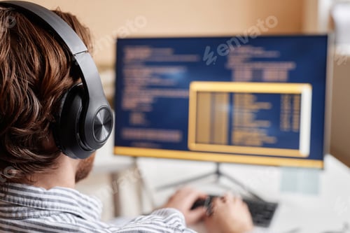 Preview: Male Computer Programmer Coding in Office and Wearing Big Headphones