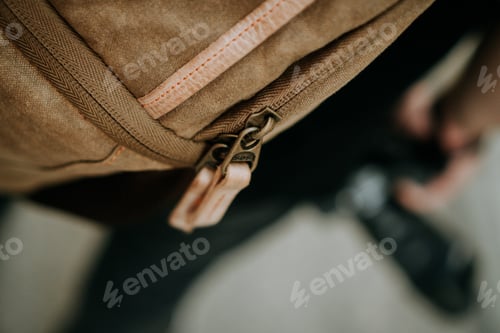 Preview: Closeup shot of the zipper pull tabs of a brown canvas camera utility bag
