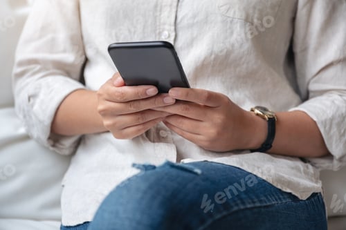 Preview: Closeup image of a woman holding , using and looking at smart phone in cafe