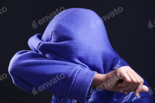 Preview: sad man in hood cover face with hands isolated in black.