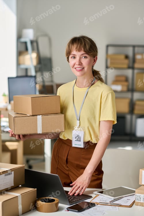 Preview: Happy young female owner of warehouse lookng at camera by workplace