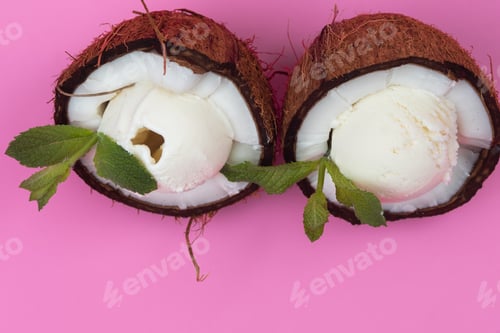 Preview: Vanilla ice cream balls in fresh coconut halves decorated with mint leaves on a pink background