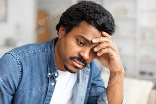 Preview: Upset Man Sitting on a Couch With Hand on Head