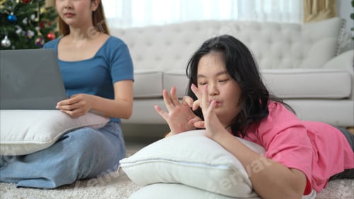 Preview: Two sisters play online games and relax in the living room at home during the holidays.