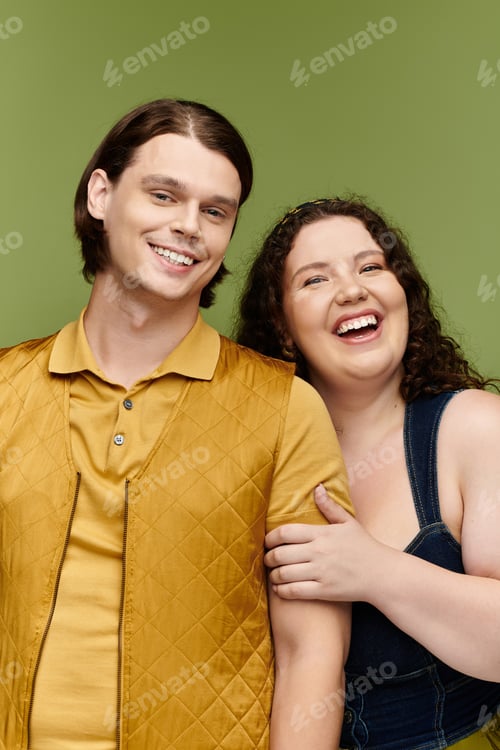Preview: A young plus size woman and her male friend share a hearty laugh in a colorful studio backdrop
