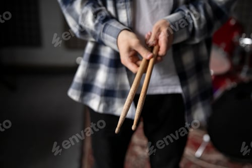 Preview: a Drummer hands Holding Drumsticks While Standing in a Rehearsal Studio