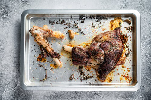 Preview: Roasted lamb mutton whole leg in a baking dish. White background. Top view
