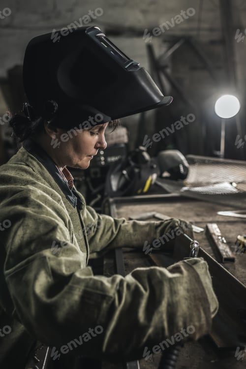 Preview: focused female manual worker in protective wear in workshop