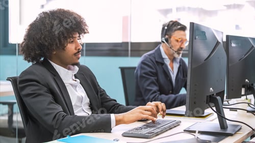 Preview: Young black businessman using computer at desk in creative workspace