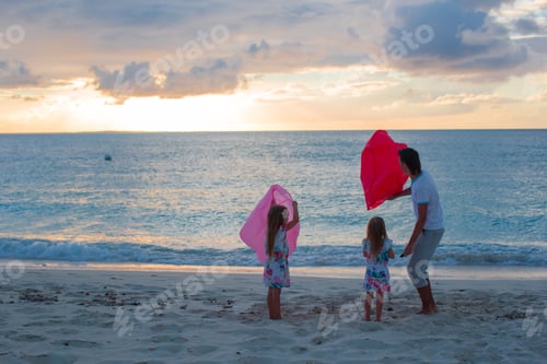 Preview: Young family enjoying sunset on the beach