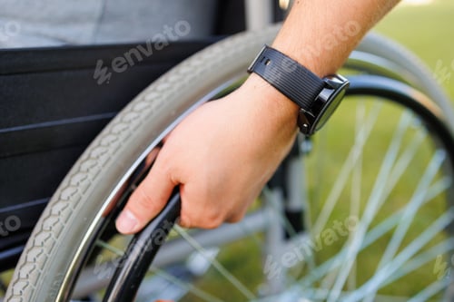 Preview: Close-Up: Hand of Young Man in Wheelchair Enjoying Outdoors