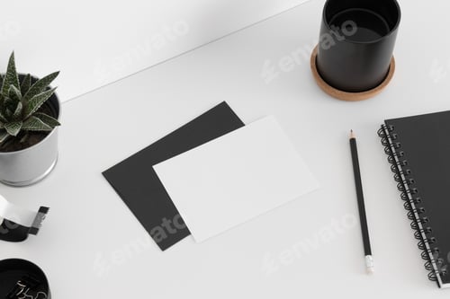 Preview: Top view of a white card mockup and envelope with a succulent and workspace accessories.
