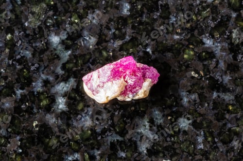Preview: sample of raw pink ruby mineral on black granite