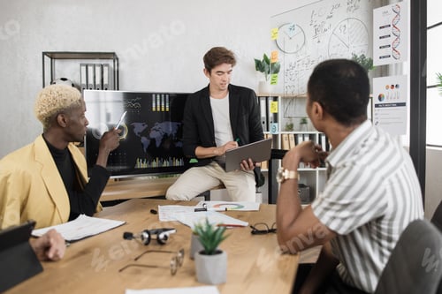 Preview: Male company worker in formal wear sitting at office desk and listening to team leader.