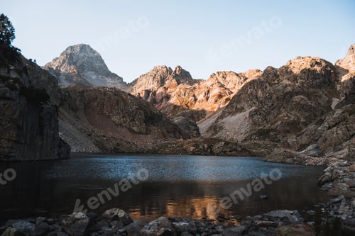 Preview: A serene lake surrounded by rocky peaks in the Pyrenees during a summer morning.