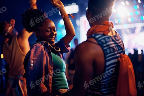 Preview: Happy black woman dancing with her boyfriend during open air music concert at night.