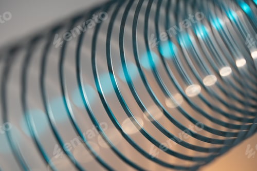 Preview: Closeup of coiled metal spring with sufficiently high strength and elastic properties in neon light