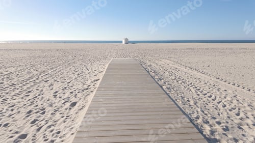 Preview: A wide wooden walkway stretches across a vast, pristine beach