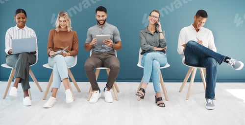 Preview: Diverse group of confident business men and women browsing on technology devices while sitting on c