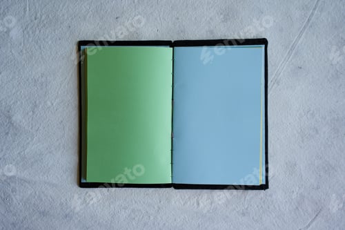 Preview: Top view of an open notebook with blank green and blue sheets isolated on a white background