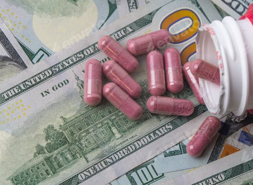 Preview: Pill capsules spilled on the table with US hundred dollar bills
