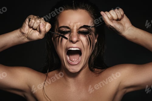 Preview: Woman with smudges of makeup on her face and broken mascara brushes