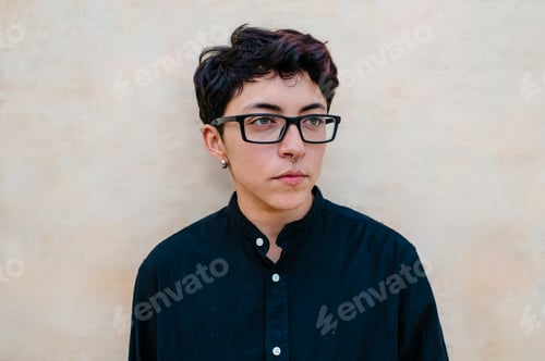 Preview: Close up view of a young transgender man looking on a wall.