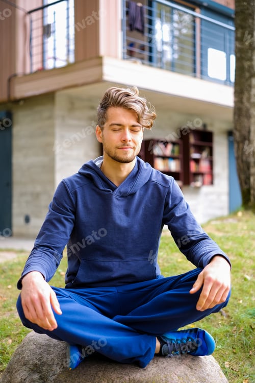 Preview: Young man meditating in public park. Concept of an active and healthy lifestyle