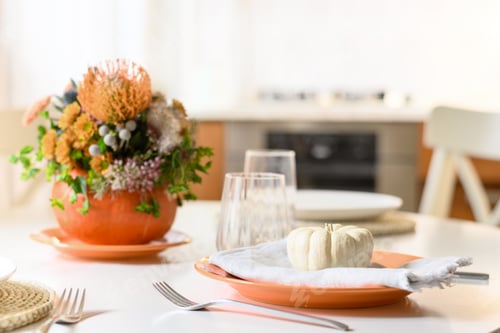 Preview: Thanksgiving day table setting decoration centerpieces with orange flowers in pumpkins.