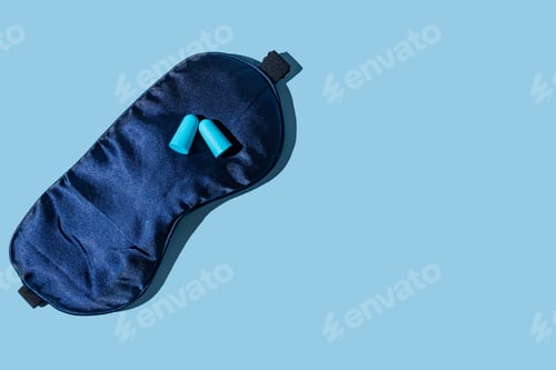 Preview: Pair of blue ear plugs and sleeping mask on light blue background, flat lay with copy space