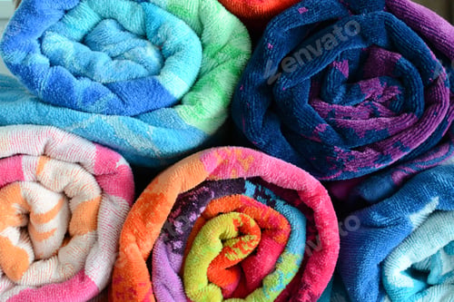 Preview: Bright and colorful rolled beach towels stacked on top of each other. Spiral rolls