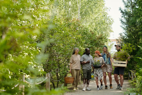 Preview: Diverse Group of Young Adults and Senior Walking Outdoors Carrying Plants