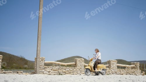 Preview: Summer landscape with a man. Action. A handsome man with long hair on a small green motorcycle on a