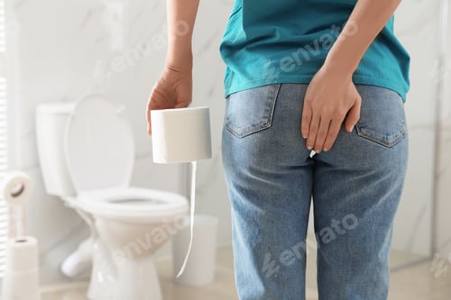 Preview: Woman with toilet paper suffering from hemorrhoid in rest room, closeup