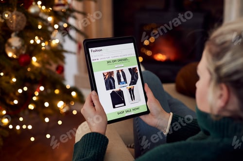 Preview: Woman At Home Using Digital Tablet To Shop For Clothes Online At Christmas