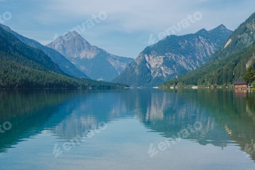 Preview: Tranquil reflections of mountains and trees in the serene waters of Plansee, Austria